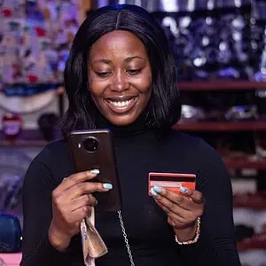 African American Woman Using a phone in a shop and paying with a card